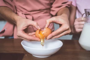 une femme cassant un oeuf pour savoir si il est encore bon