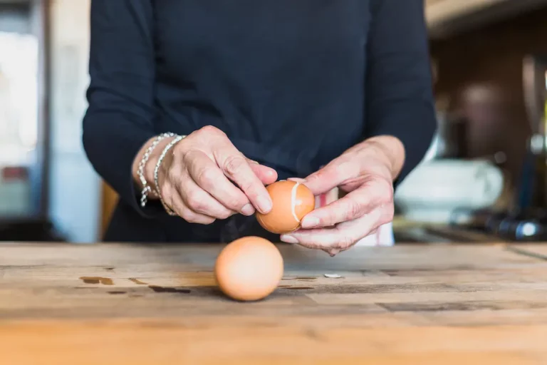 mains d'une femme qui écale des oeufs durs
