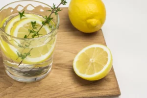 verre d'eau citronnée sur une planche à découper avec des citrons